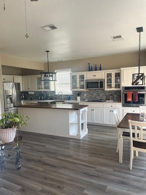 kitchen with sink, appliances with stainless steel finishes, decorative light fixtures, dark hardwood / wood-style flooring, and white cabinetry