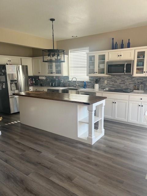 kitchen featuring sink, white cabinets, pendant lighting, a kitchen island, and appliances with stainless steel finishes