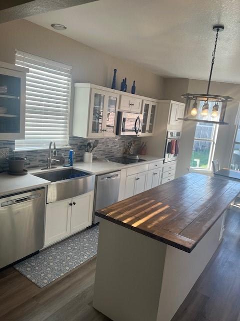 kitchen featuring plenty of natural light, white cabinets, hanging light fixtures, and appliances with stainless steel finishes