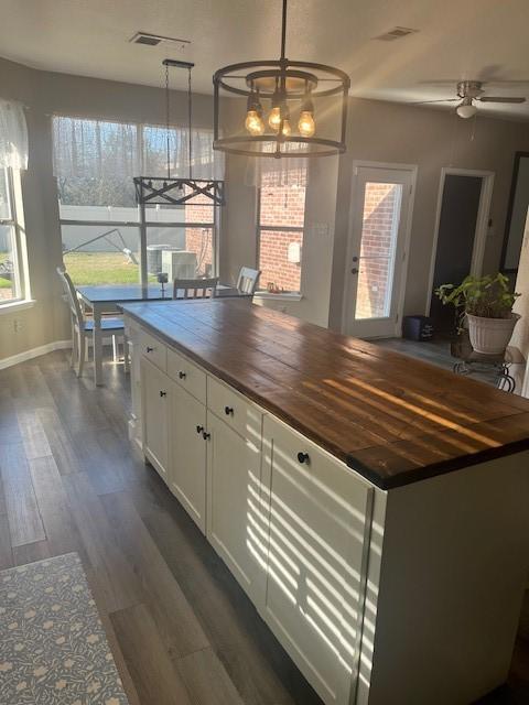 kitchen featuring ceiling fan with notable chandelier, dark hardwood / wood-style floors, butcher block countertops, decorative light fixtures, and white cabinetry