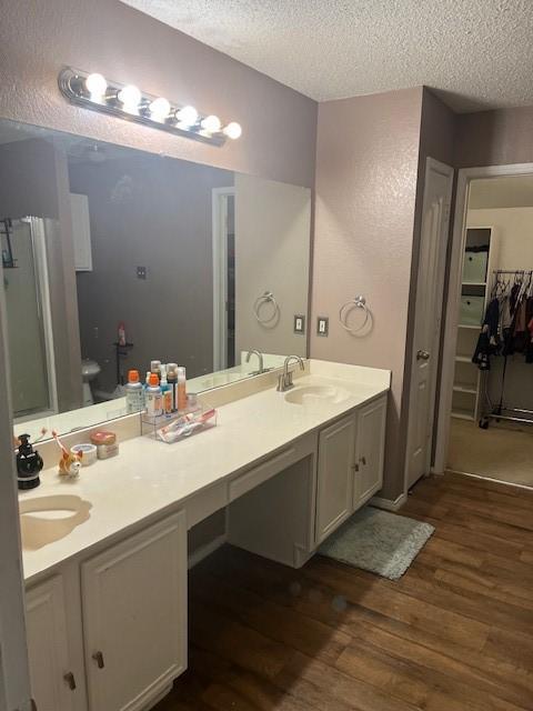 bathroom featuring a textured ceiling, vanity, toilet, and wood-type flooring