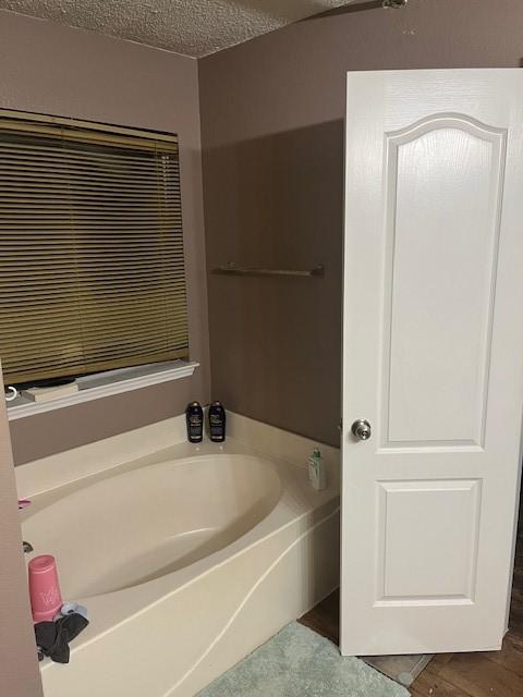 bathroom with a washtub and a textured ceiling