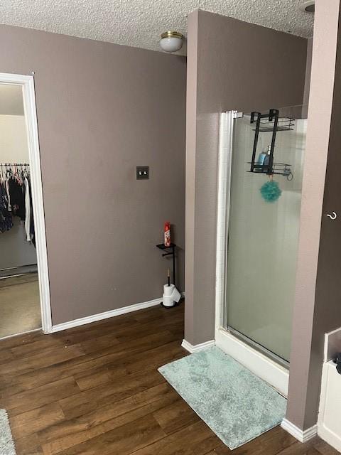 bathroom with hardwood / wood-style flooring, a shower with door, and a textured ceiling