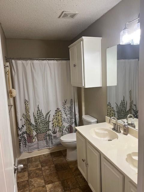 full bathroom featuring vanity, shower / bathtub combination with curtain, a textured ceiling, and toilet