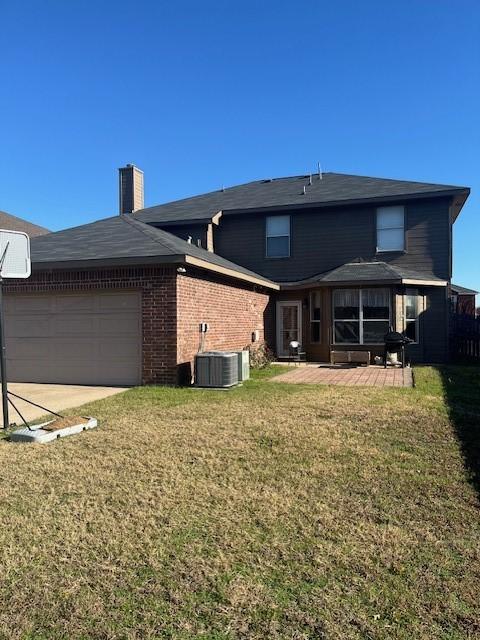 rear view of property with central AC unit, a garage, and a lawn