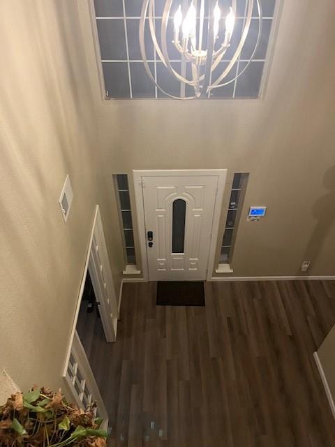 entrance foyer featuring a towering ceiling, dark wood-type flooring, and a notable chandelier