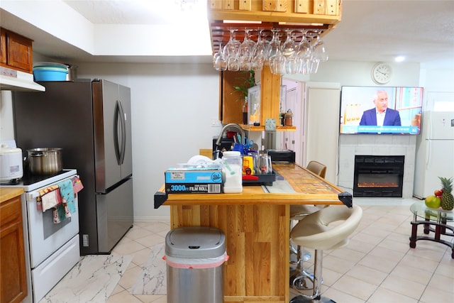 kitchen featuring a breakfast bar area, a tile fireplace, and white appliances