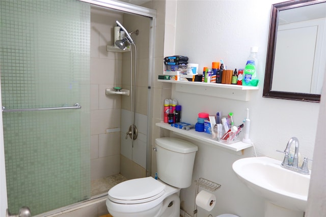 bathroom featuring toilet, a shower with shower door, and sink