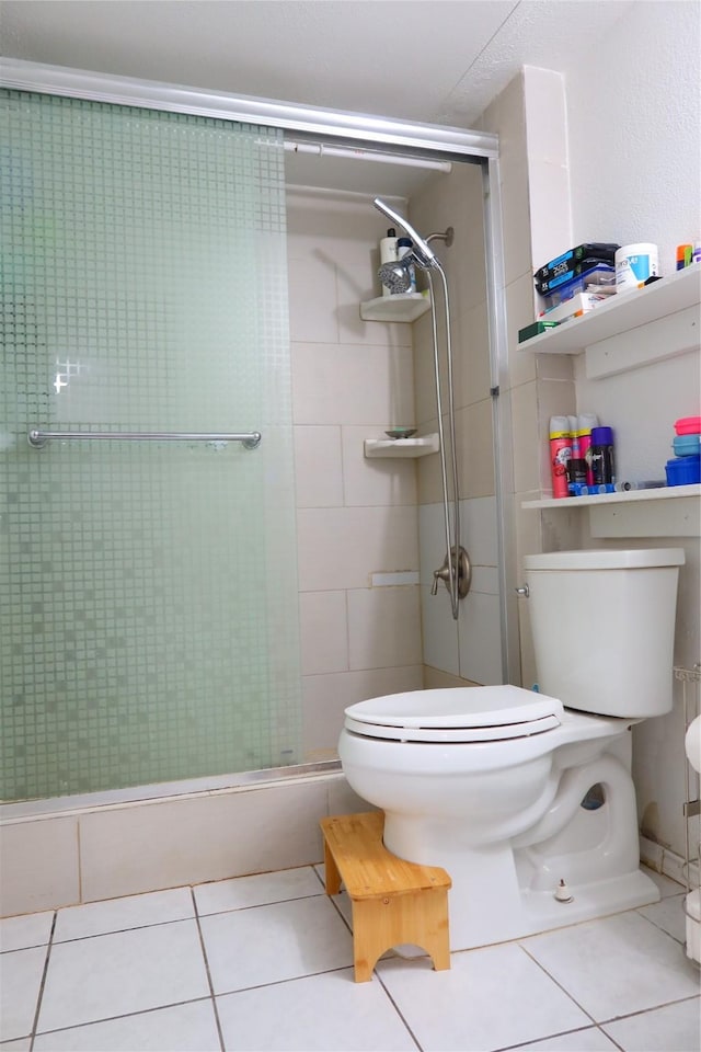 bathroom with tile patterned floors, toilet, and a shower with shower door