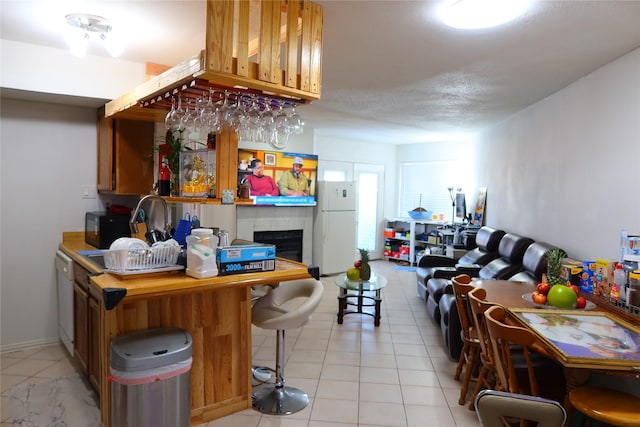 interior space with kitchen peninsula, white appliances, a breakfast bar area, and a tile fireplace