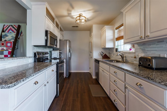 kitchen featuring white cabinetry, sink, dark hardwood / wood-style floors, dark stone counters, and appliances with stainless steel finishes