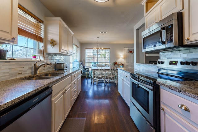 kitchen featuring sink, a notable chandelier, decorative light fixtures, decorative backsplash, and appliances with stainless steel finishes