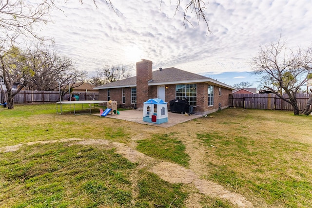 rear view of house with a lawn, a trampoline, and a patio