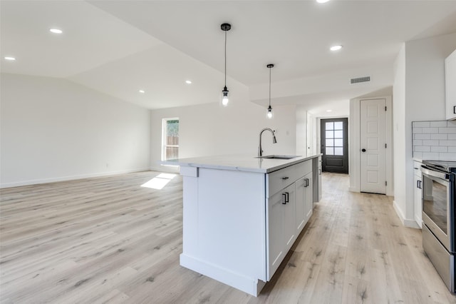 kitchen with sink, decorative light fixtures, electric stove, a center island with sink, and white cabinets