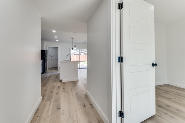 hall with light wood-type flooring and sink