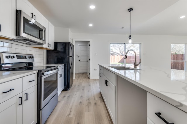 kitchen featuring tasteful backsplash, stainless steel appliances, sink, pendant lighting, and white cabinetry