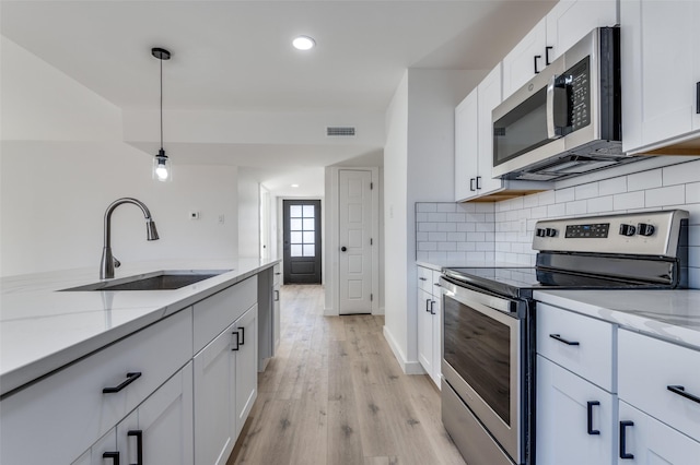 kitchen featuring white cabinetry, sink, pendant lighting, and appliances with stainless steel finishes