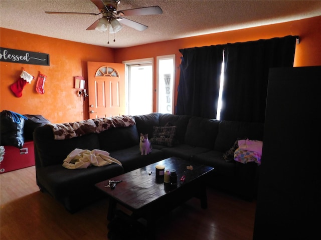 living room with a textured ceiling, ceiling fan, and wood-type flooring