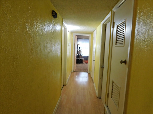 hall featuring a textured ceiling and light hardwood / wood-style floors