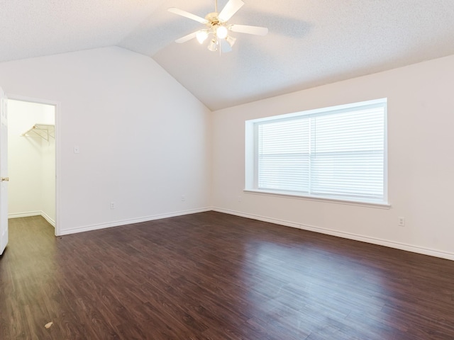 spare room featuring dark hardwood / wood-style floors, ceiling fan, lofted ceiling, and a textured ceiling