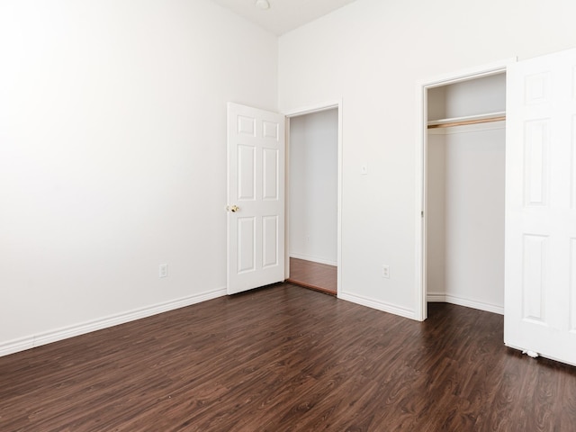 unfurnished bedroom with dark hardwood / wood-style flooring and a closet