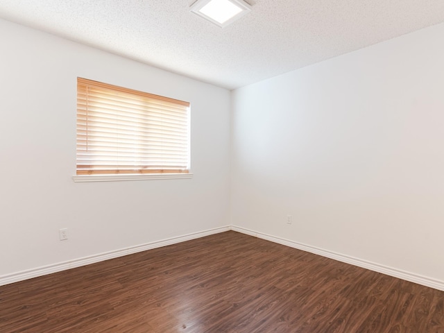 empty room with dark hardwood / wood-style floors and a textured ceiling