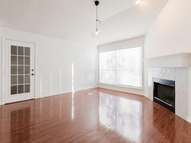 unfurnished living room featuring a textured ceiling, a tile fireplace, wood-type flooring, and vaulted ceiling