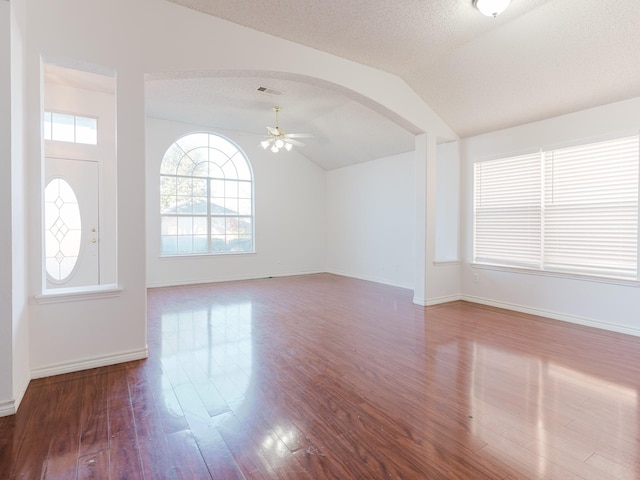 unfurnished living room with hardwood / wood-style flooring, ceiling fan, lofted ceiling, and a textured ceiling