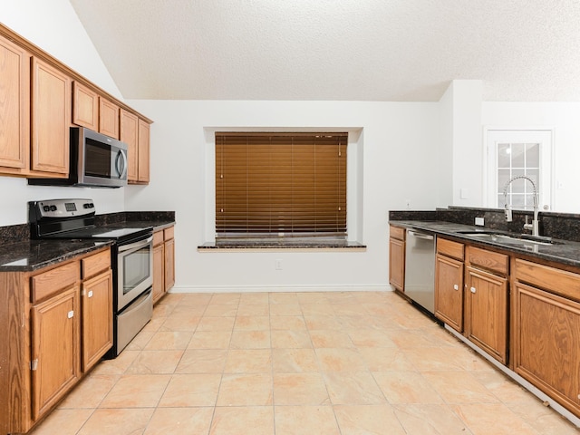 kitchen featuring dark stone countertops, sink, stainless steel appliances, and a textured ceiling