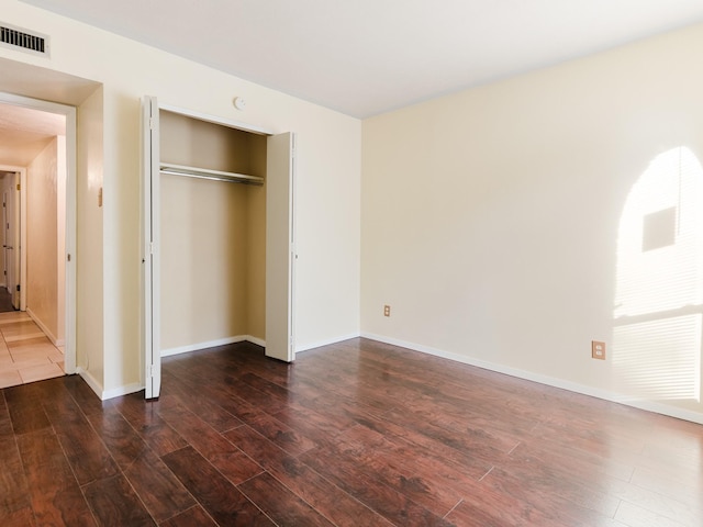 unfurnished bedroom featuring a closet and dark hardwood / wood-style floors