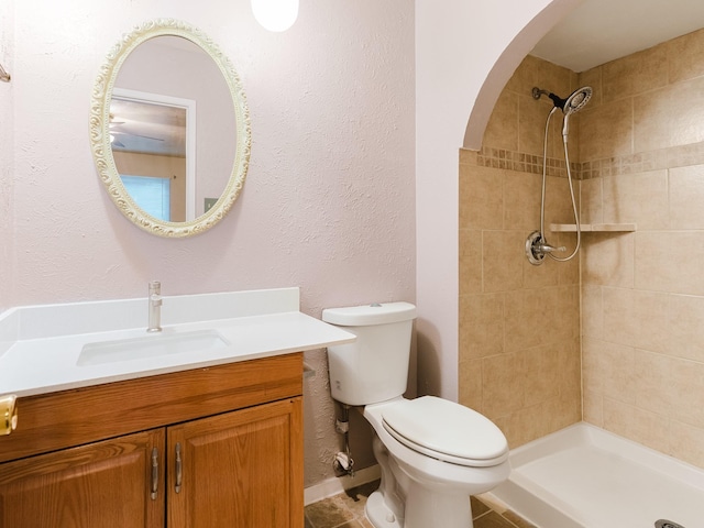 bathroom with vanity, toilet, and a tile shower