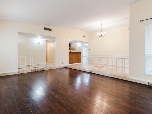 spare room featuring wood-type flooring, lofted ceiling, and an inviting chandelier