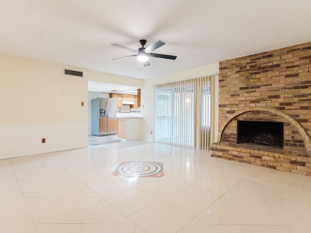 unfurnished living room featuring a brick fireplace, light tile patterned floors, and ceiling fan