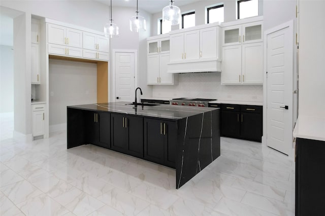 kitchen with sink, white cabinetry, and a kitchen island with sink