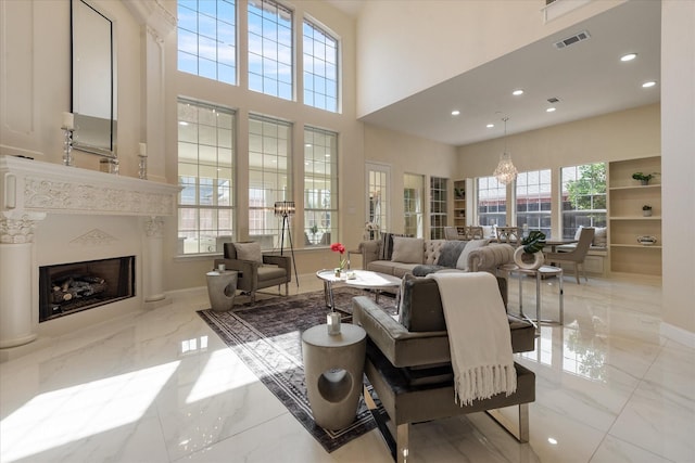 living area with marble finish floor, visible vents, a high ceiling, a premium fireplace, and baseboards