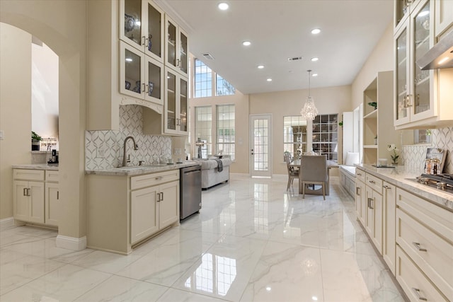 kitchen featuring dishwasher, sink, hanging light fixtures, tasteful backsplash, and light stone counters