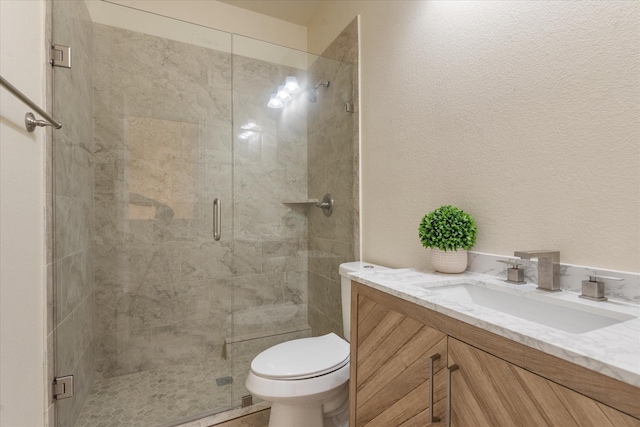 full bathroom with a textured wall, a stall shower, vanity, and toilet