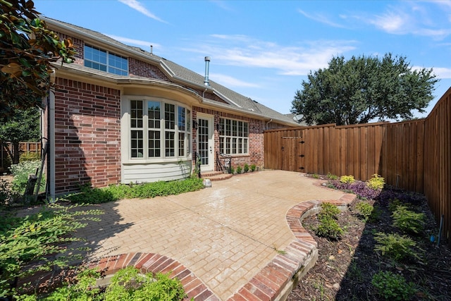 rear view of property featuring brick siding, a patio area, and a fenced backyard