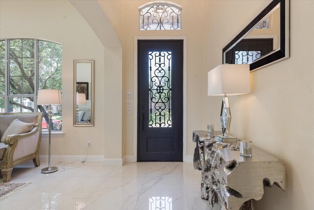 entryway with marble finish floor, a healthy amount of sunlight, and baseboards