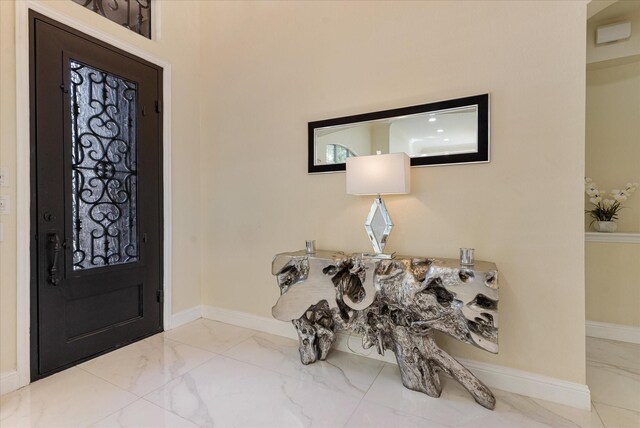 foyer with marble finish floor and baseboards