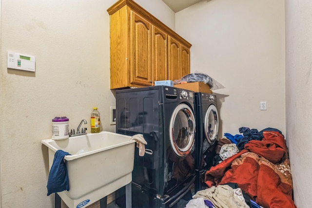 clothes washing area with cabinets, sink, and washer and clothes dryer