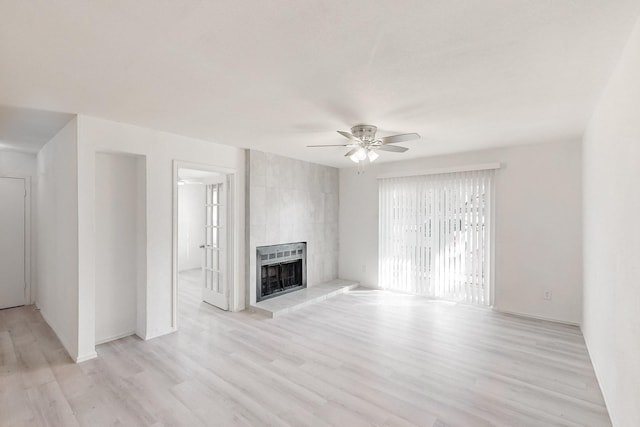 unfurnished living room featuring heating unit, ceiling fan, a tiled fireplace, and light hardwood / wood-style flooring