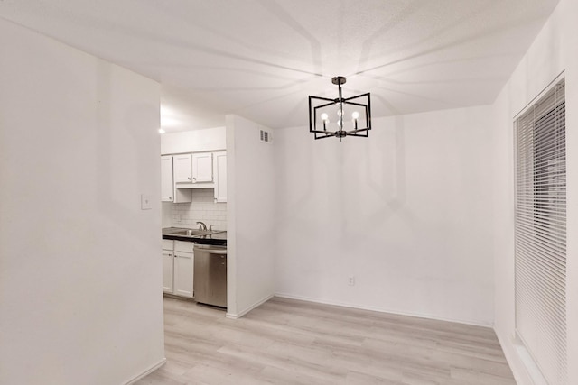 unfurnished dining area featuring sink, light wood-type flooring, and a notable chandelier