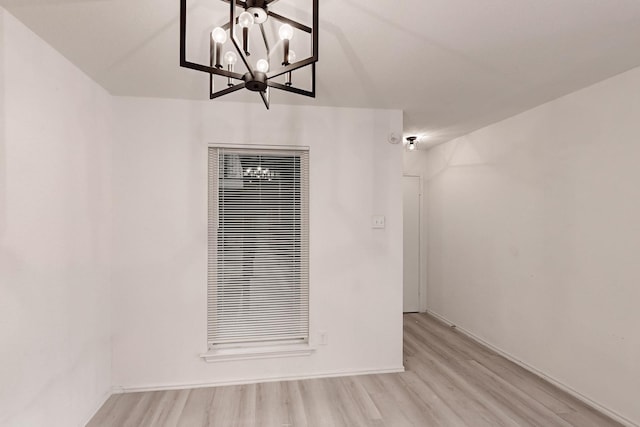 unfurnished room featuring light hardwood / wood-style flooring and a chandelier