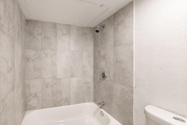 bathroom with toilet and tiled shower / bath