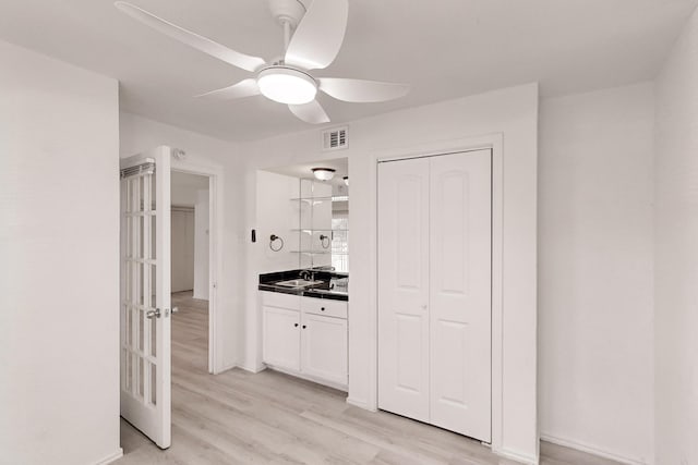 kitchen featuring white cabinets, ceiling fan, sink, and light hardwood / wood-style flooring