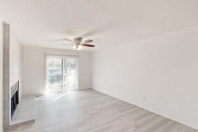 unfurnished living room with ceiling fan, light hardwood / wood-style floors, and a fireplace