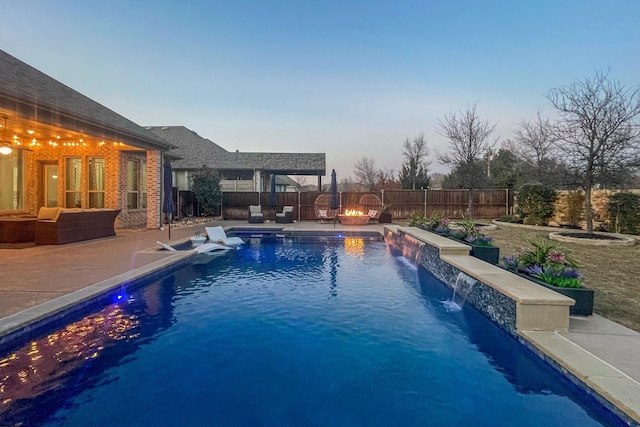 pool at dusk featuring pool water feature and a patio area