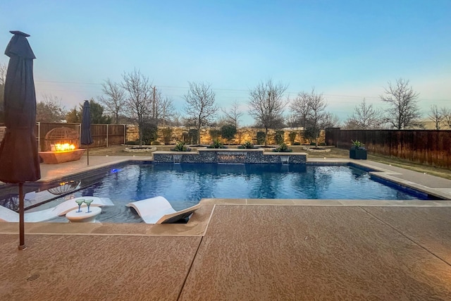 pool at dusk featuring a patio area and an outdoor fire pit