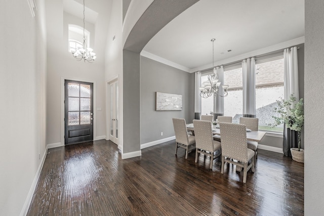 dining room with ornamental molding, dark hardwood / wood-style flooring, an inviting chandelier, and a high ceiling